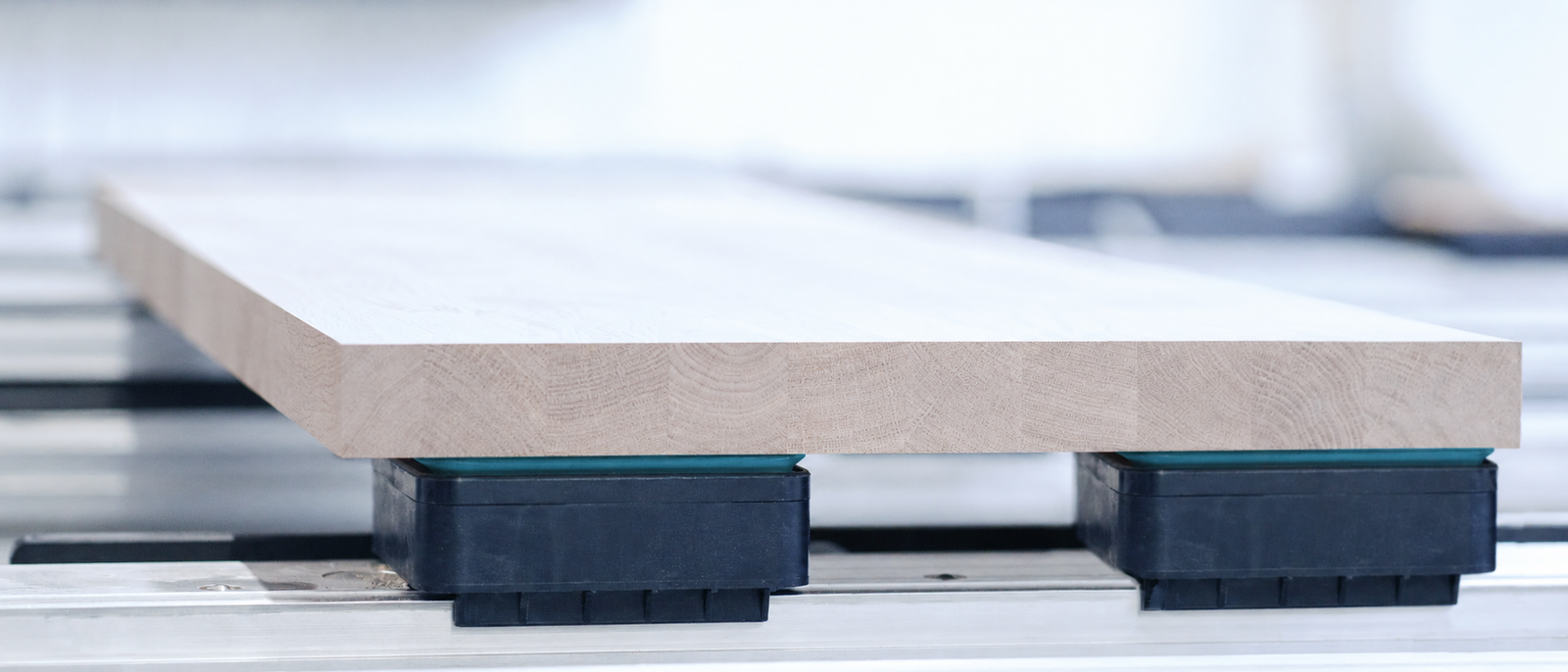 Tablero de madera sujeto sobre bloques de vacío de una mesa de mecanizado, sin manos.
